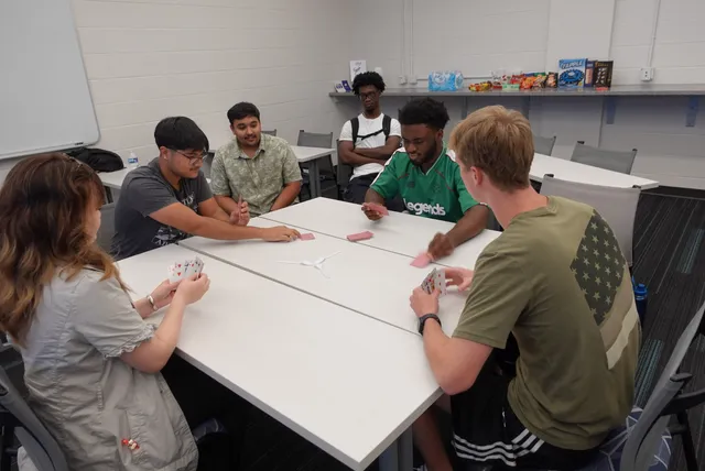 Students playing cards around a table at SISTA game night.